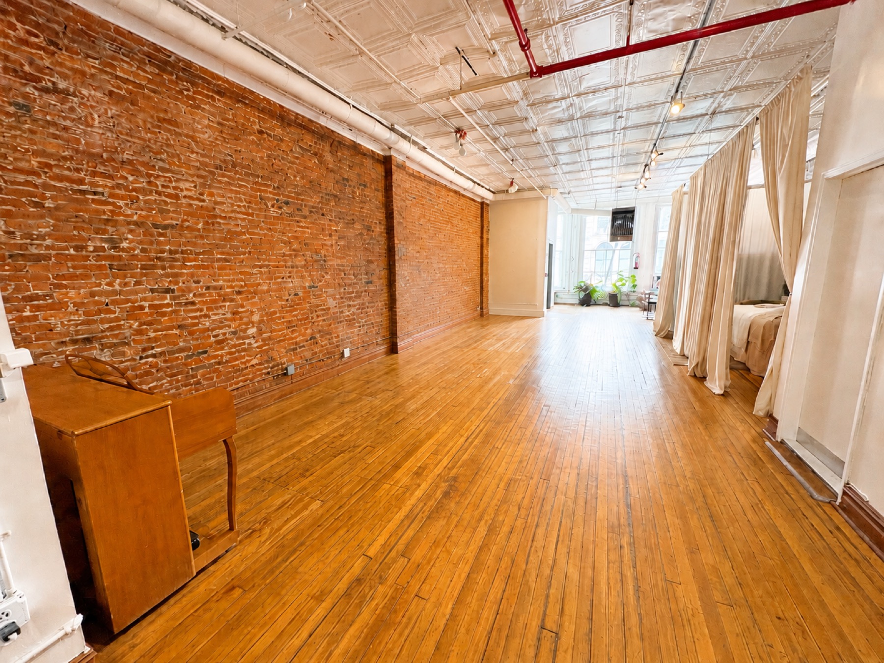 Empty exposed-brick loft with hardwood floors in daylight