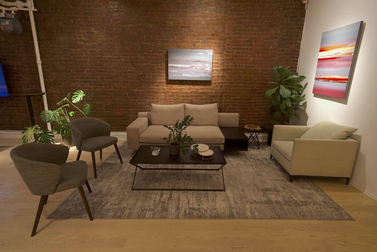 Living room set with sofas, armchairs and art against exposed brick
