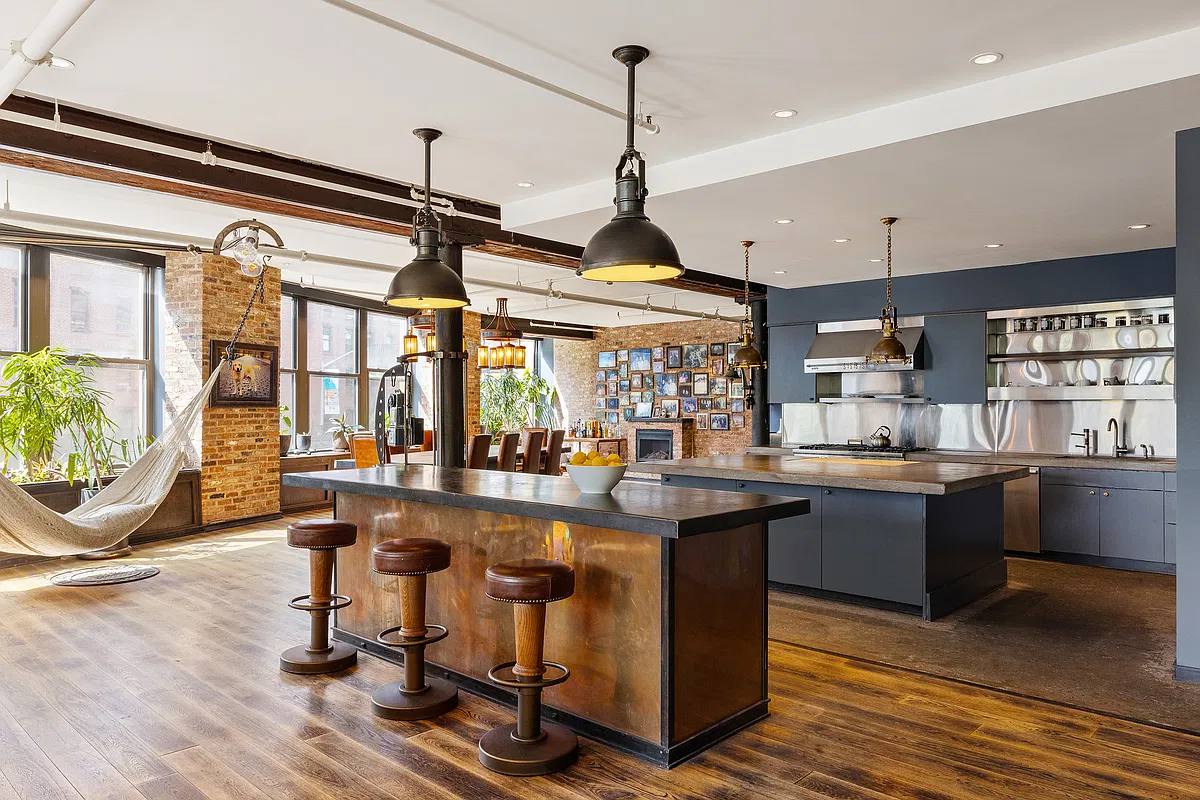 Kitchen island with leather stools under brass pendants, fireplace and photo wall behind