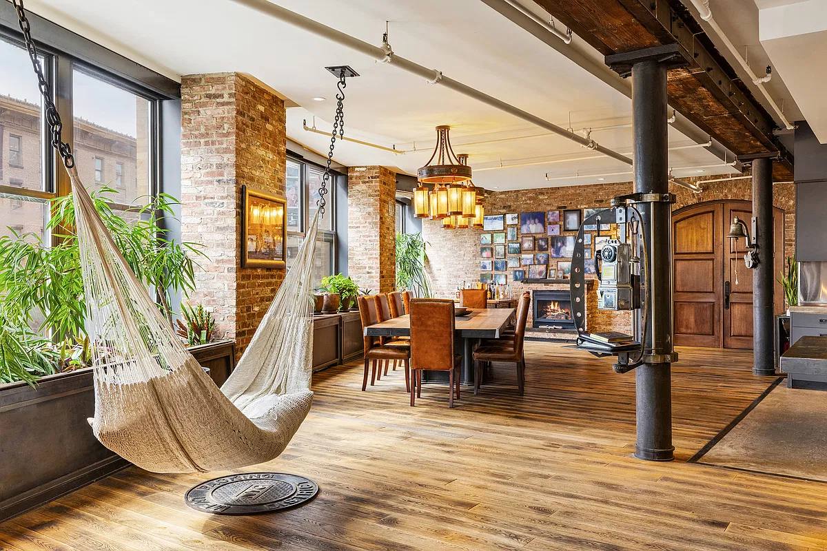 Long dining table by the fireplace, with a hammock and a wall of framed photos