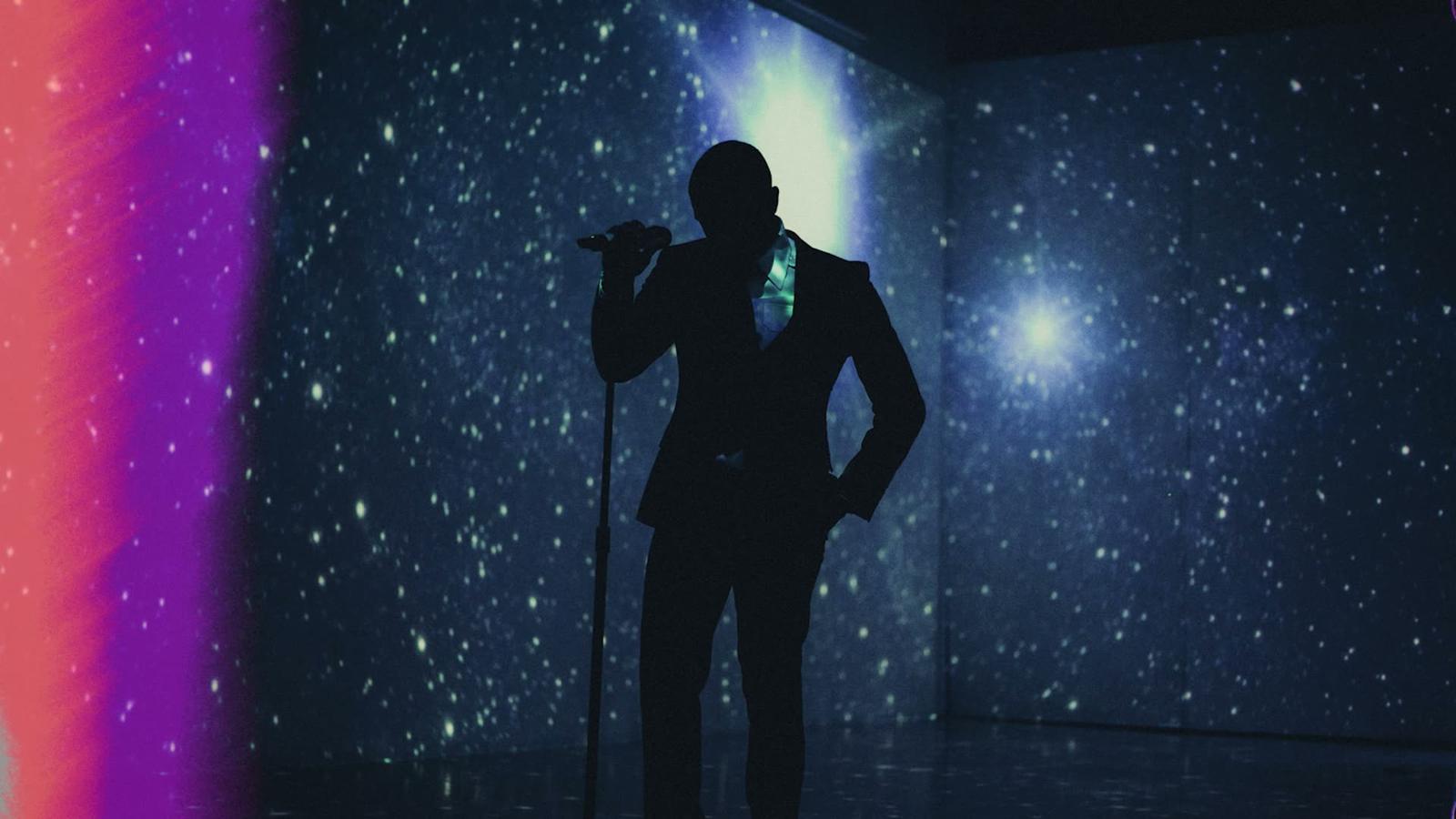 One performer in silhouette against a projected galaxy