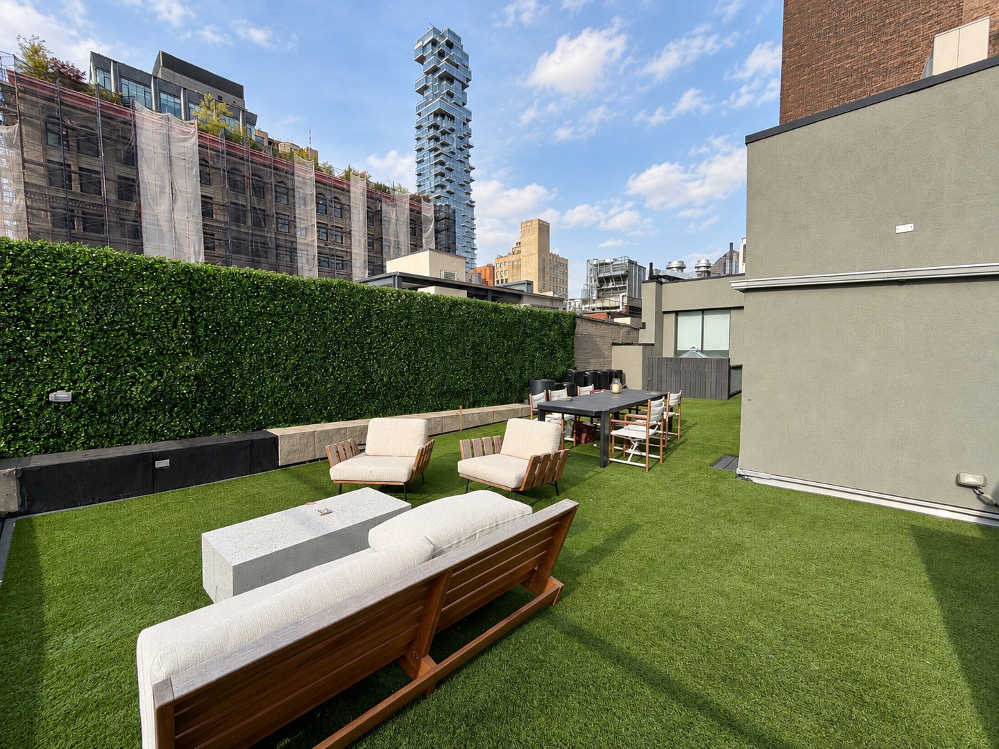 Lounge seating and dining table on the roof with 56 Leonard in the background