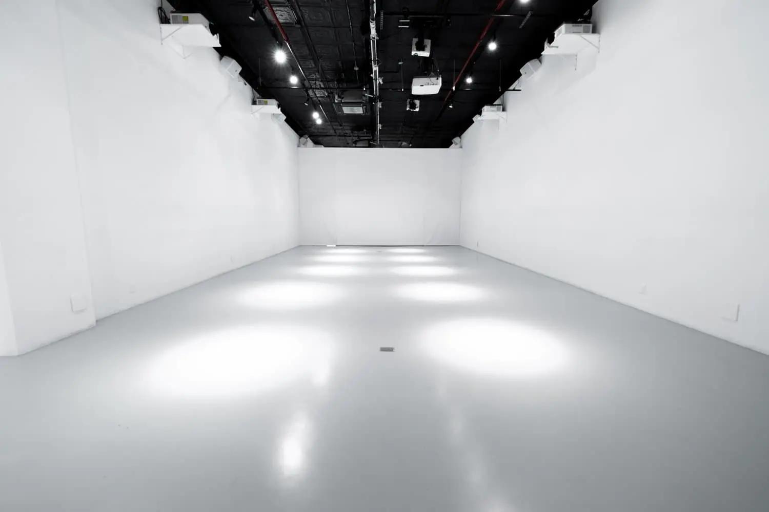 Looking down the empty white room under the black ceiling grid