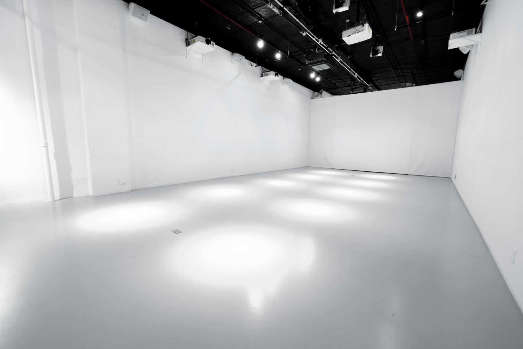 The White Box Stage empty: white walls, a glossy white floor and the black lighting grid